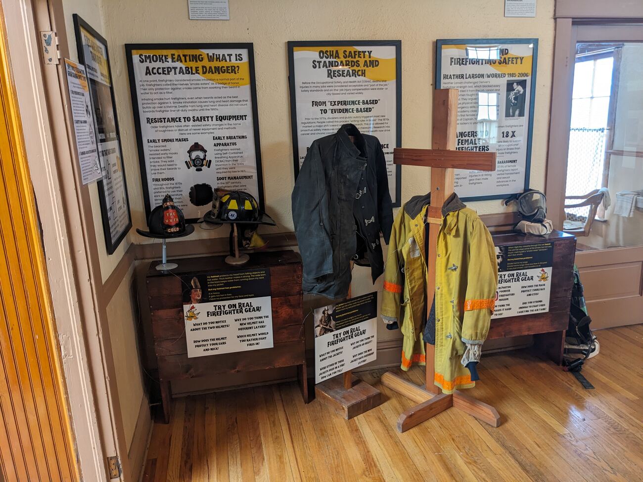 Corner installation of the Built to Protect exhibit, showing framed panels and firefighter gear on display